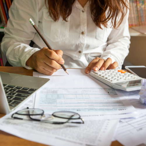 Woman comparing investment platforms like M1 Finance and Wealthfront on her laptop, using Asper AI on her phone to manage funds for investing.